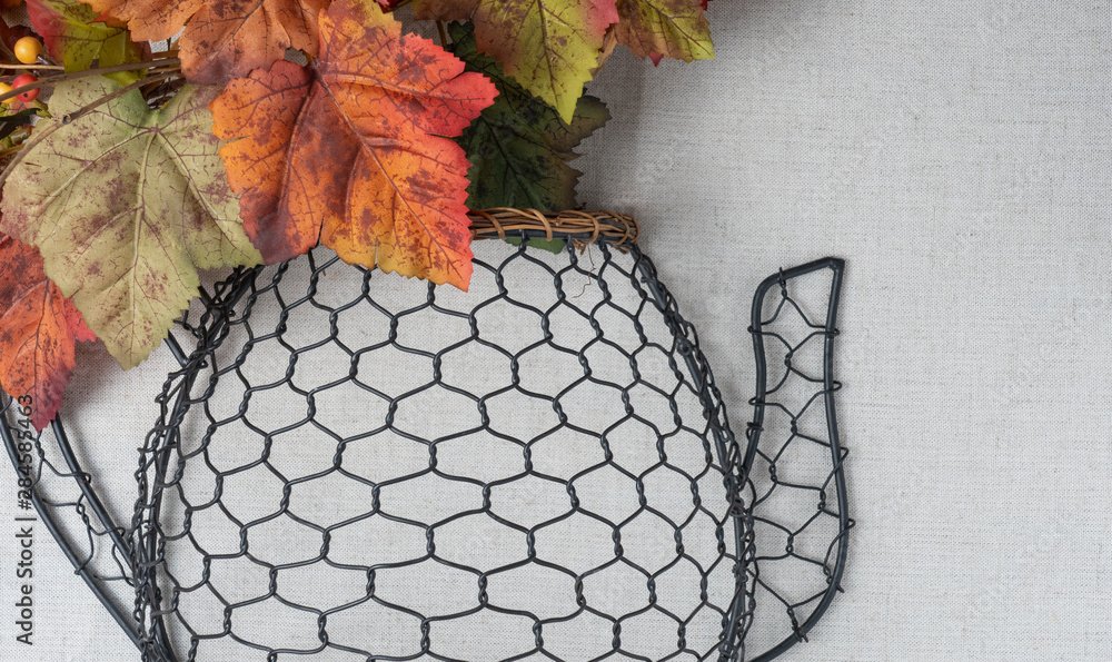 country style black chickenwire teapot decor with autumn leaves on a linen background